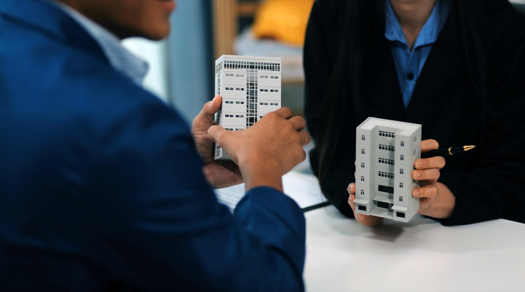 Corretores analisando maquetes de imóveis sobre a mesa