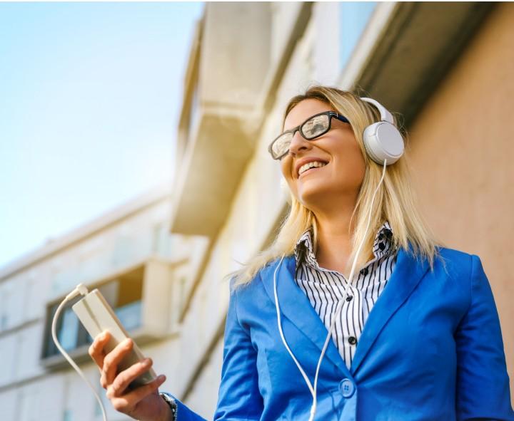 Corretora sorrindo ao ouvir uma aula com fones de ouvido